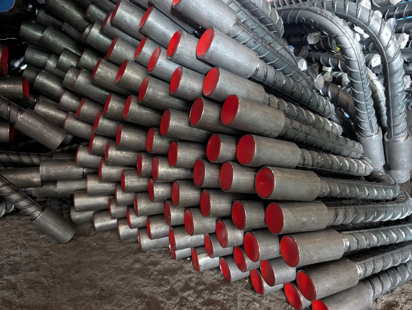 Rebar couplers with red protective caps fitted to bar ends for mechanical splicing